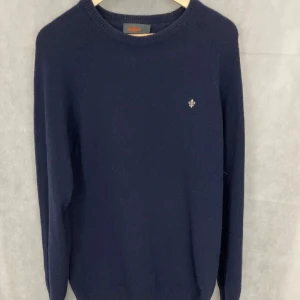 Mörkblå tröja från Morris - Snygg mörkblå tröja från Morris med en liten broderad detalj på bröstet. Tröjan har en klassisk rund hals och långa ärmar, perfekt för kyligare dagar.