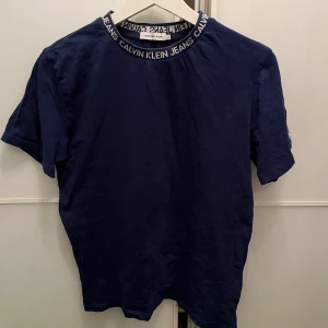 Mörkblå t-shirt från Calvin Klein Jeans - mörkblå t-shirt från Calvin Klein Jeans med logga på kragen och ett litet CK-märke på ärmen. Skick är 9/10 och är endast använd ett fåtal gånger 