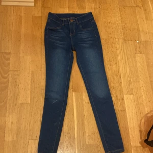 Blå jeansbyxor från Ehcilbea - Snygga blå jeansbyxor från Ehcilbea med hög midja och skinny passform. De har klassiska fem fickor och en knappstängning framtill. Perfekta för en stilren look.