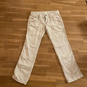 Vita lågmidjade jeans från Diesel - Säljer ett par snygga vita lågmidjade jeans från Diesel med en snygg femficksdesign och kontrastsömmar. Byxorna har en pytte lite boot cut  passform men absolut inte skinny jeans. Jeansen är som nya. Perfekta för en stilren look. Priset kan diskuteras.🫶