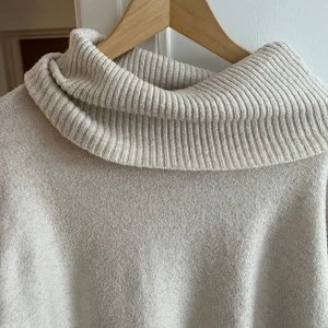 Beige polotröja från Vero Moda - Mysig beige polotröja från Vero Moda. Tröjan har en ribbad polokrage och ribbade muddar vid ärmslut och nederkant. Perfekt för kyliga dagar.