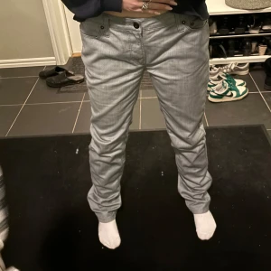 Grå jeans  - Snygga grå byxor med normal passform och låg midja. Perfekta för en avslappnad stil. Byxorna har en klassisk design med knappar och dragkedja framtill.