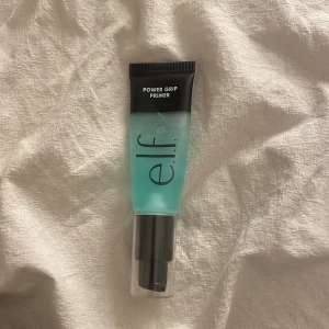 e.l.f. Power Grip Primer - Säljer en e.l.f. Power Grip Primer i en turkos tub med svart lock. Primern har en gel-liknande konsistens och är designad för att ge en jämn bas för smink. Perfekt för att få sminket att hålla längre och se fräscht ut hela dagen.