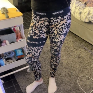 Leopardmönstrade leggings från Stronger - Snygga leopardmönstrade leggings från Stronger med hög midja. Perfekta för träning eller en avslappnad dag. De har en elastisk midja med logotypdetaljer och är gjorda i ett stretchigt material för bästa komfort.