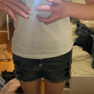 Svarta jeansshorts med slitningar - Snygga svarta jeansshorts med slitna detaljer och fransig kant. De har en hög midja och knappar framtill. Perfekta för en avslappnad stil. Det är xs men skulle passa small. ❣️❣️