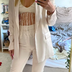  Vit/creme/ljus beige kavaj+ byxa från Zara - Snygg vit/creme kavaj (M) + byxa (S) från Zara i ett elegant och stilrent snitt. Perfekt för att lyfta vilken outfit som helst. Använd 1 gång och blev lite skrynklig i tvätten. Behöver strykas. Kavajen har en klassisk design med knappar och fickor framtill.