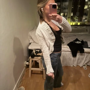 Vit stickad kofta/cardigan - Säljer en vit stickad kofta med långärmad design. Koftan har en öppen front och ribbade detaljer vid ärmslut och nederkant. Perfekt för att hålla sig varm och stilren. Skön för sommarkvällar. Saknar lapp så okänt märke samt storlek, men uppskattad storlek är S/XS 