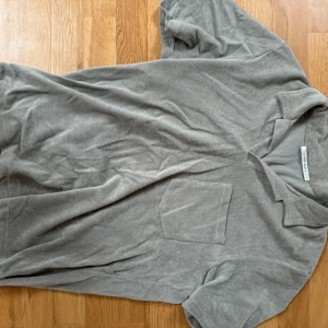 Grå frotté t-shirt från A Day's March - Säljer en stilren grå t-shirt i frotté från A Day's March. Den har en klassisk krage och en bröstficka som ger en avslappnad look. Perfekt för en casual stil. Använd några gånger, storlek S