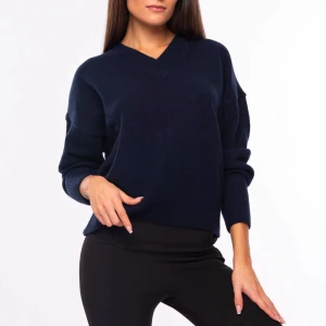 Mörkblå tröja från ELS - Säljer en cashmere tröja stilren mörkblå tröja från ELS med v-ringning. Tröjan har långa ärmar och ribbade muddar vid ärmslut och nederkant, vilket ger en klassisk look. Perfekt för kyligare dagar. Är inte från den bilden men en likande köpt på Lucca