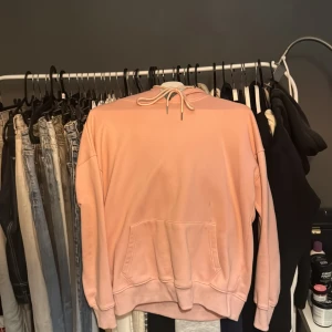 Rosa hoodie från Madlady - Säljer en snygg rosa hoodie från Madlady. Den har en klassisk design med dragsko i huvan och en stor magficka framtill. Perfekt för en avslappnad stil. Passar bra till jeans eller leggings.