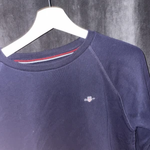 Mörkblå tröja från GANT - Säljer en stilren mörkblå tröja från GANT med rund halsringning och diskret logga på bröstet. Perfekt för en avslappnad och snygg look. Säljs för endast 199kr! Pris går att diskuteras om man följer! Mvh Småland, bolaget 