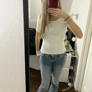 Vit ribbad topp från Lindex - Säljer en stilren vit ribbad topp från Lindex. Perfekt nu till våren. Toppen har en tight passform och korta ärmar, perfekt för en enkel och snygg look. Tillverkad i ett mjukt och bekvämt material och aldrig använd! 