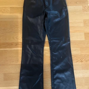 Svarta skinnbyxor - Snygga svarta skinnbyxor med en stilren design. Byxorna har en rak passform och är perfekta för en trendig look. De har en klassisk midja och stängs med dragkedja och knapp framtill.