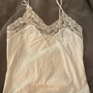 Vit linne med spetsdetaljer - Jättefin spetstopp/pyjamaslinne med spets och rosetter. Två tunna axelband vilket gör en liten fin detalj! Jättefin men används inte. Det var som en lite större storlek tidigare (44) men jag sydde till axelbanden så de blev kortare och då är den som en S eller M!