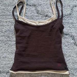 Brun och beige linnetopp - Snygg brun och beige linnetopp med dubbla axelband från Urban Outfitters. Toppen har en kontrasterande kant i beige som ger en cool lager-på-lager-effekt.