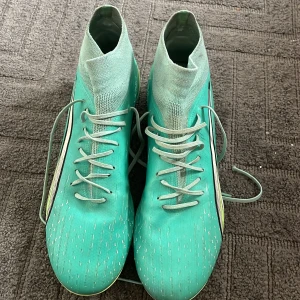  Puma Ultra fotbollsskor - Säljer ett par turkosa Puma Ultra med strumpa, nypris 1200!!!. Fungerar bra på både konstgräs och naturgräs. Skorna är använda men är i bra skick. Storlek 43, UK 9. Lägre pris kan diskuteras.