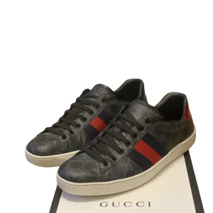 Gucci ace  - Snygga svarta sneakers från Gucci med ikoniskt mönster och röd-blå rand på sidan. Skorna har svarta snören och en vit sula med detaljerad design undertill. Perfekta för en stilren look.mch scandic fashion