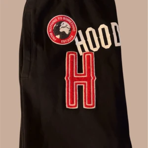 Svarta mjukisbyxor från Hoodrich - Snygga svarta mjukisbyxor från Hoodrich med coola tryck och broderade detaljer. Byxorna har elastisk midja med snörning och praktiska sidofickor. Perfekta för en avslappnad stil.