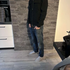 Svart jacka från Selected Homme - Snygg svart jacka från Selected Homme i storlek S. Jackan har en dragkedja framtill och långa ärmar med knappdetaljer vid ärmsluten. Perfekt för en stilren look.
