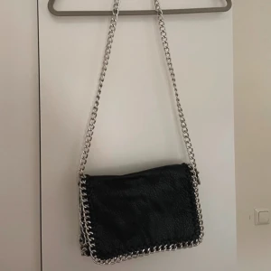 Svart axelväska med silver kedja  - Säljer en snygg svart axelväska med silver kedja. Väskan är från Tiamo 💕