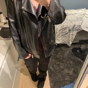 Svart skinnjacka från Stories - Snygg svart skinnjacka från Stories i storlek S Jackan har flera dragkedjor och ett bälte i midjan. Jackan har en oversized passform och är använd ett fåtal gånger.