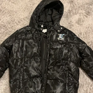 Svart pufferjacka från Juicy Couture - säljer en svart pufferjacka från Juicy Couture med kamouflage mönster. passar xs-m o i perfekt skick men har dock några katt märken o några små hål. hålen är vid vristen på undersidan så det är inget som riktigt syns💞