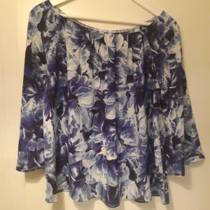 Blommig offshoulder topp i vit/blå - Säljer en superfin blommig offshoulder topp i blå och vit från Bikbok. Oanvänd i flera år, I gott skick.