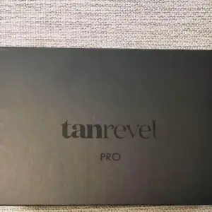 Säljer ett Tanrevel Pro Kit som innehåller en elegant svart enhet och en flaska tanning liquid. Perfekt för att få en jämn och naturlig solbränna hemma. Kommer i en stilren svart förpackning med plats för både enheten och vätskan. Perfekt för dig som vill ha en solkysst look året runt!