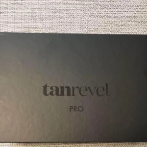 Tanrevel Pro Kit - Säljer ett Tanrevel Pro Kit som innehåller en elegant svart enhet och en flaska tanning liquid. Perfekt för att få en jämn och naturlig solbränna hemma. Kommer i en stilren svart förpackning med plats för både enheten och vätskan. Perfekt för dig som vill ha en solkysst look året runt!