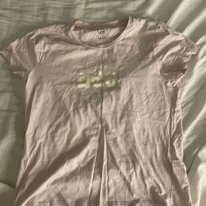 Ljusrosa t-shirt från Lee - Säljer en ljusrosa t-shirt från Lee i storlek XS. Den är i bomull och har en normal passform med korta ärmar. Perfekt för vardagsbruk med en enkel och stilren design. Loggan är tryckt på framsidan. Supermysigt att ha som en hemmatröja!