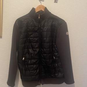 Säljer en snygg svart jacka från Moncler 8/10 skick. Den har en quiltad framsida med dragkedja och två praktiska fickor. Perfekt för höst och vår när du vill hålla stilen. Jackan har långa ärmar och en hög krage för extra värme. Passar både till vardags och lite finare tillfällen. Cardigan är i storlek S men passar också bra som M