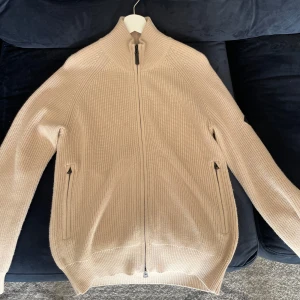 Beige Kofta J.Lindeberg - Säljer en snygg beige stickad kofta från J.Lindeberg. Storleken på koftan är S. Ny pris på denna koftan är 2500kr, tar även byten. Koftan är i mycket bra skick.. Perfekt för både höst och vinter!💯