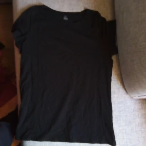 Svart t-shirt från KappAhl - Säljer en svart t-shirt från KappAhl i storlek XL. Den är gjord av ekologisk bomull och är supermjuk och bekväm. Perfekt för vardagsbruk eller att ha under en snygg jacka. T-shirten har en klassisk passform och korta ärmar. Ett måste i basgarderoben!