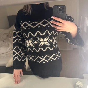 Svart och vit mönstrad stickad tröja - Säljer en superfin svart stickad tröja med vitt geometriskt mönster. Den har en hög krage och långa ärmar, perfekt för kyliga dagar.Perfekt för både höst och vinter! Tröjan är i nytt skick och har aldrig använt! Passar S och XS! För prisförslag skriv privat!