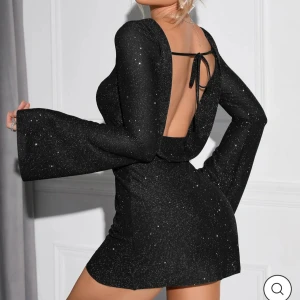 Parthea klänning - Snygg svart klänning med glittrigt mönster och öppen rygg. Den har långa ärmar och en tight passform som framhäver figuren. Perfekt för festliga tillfällen! Köpt från Parthea, endast använd vid 1 tillfälle💞