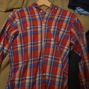 Rutig skjorta från Ralph Lauren - Säljer en snygg rutig skjorta från Ralph Lauren i rött, blått och grönt. Skjortan är långärmad och har klassiska knappar framtill. Perfekt för både vardag och fest! 🕺