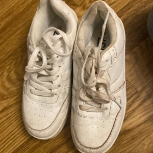 Vita sneakers med snörning - Säljer ett par vita sneakers i bra skick. De har klassisk snörning och en stilren design. Perfekta för vardagsbruk och passar till det mesta. Lite smuts på sulan men annars i fint skick. Perfekt för dig som vill ha en enkel och stilren look.