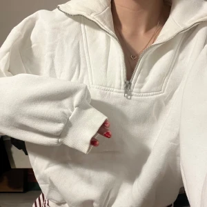 Vit hoodie med dragkedja - Säljer en supermjuk och bekväm vit hoodie med dragkedja. Perfekt för kyliga dagar eller mysiga hemmakvällar. Den har en hög krage och långa ärmar med ribbade muddar. Passar till allt och är ett måste i garderoben! 🤍Säljer även en likadan i svart!