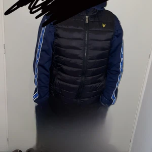 Svart pufferjacka från Lyle & Scott Junior - Säljer en svart pufferjacka från Lyle & Scott Junior i mycket bra skick. Jackan har en dragkedja framtill och är perfekt för höst. och har en gul logga på bröstet. Perfekt för att hålla sig varm och stilren! 🖤