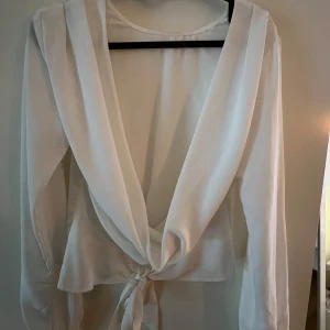 Vit blus med öppen rygg - Perfekt blus - stilren fram och öppen rygg. Saknar knapp på handleden - inget som syns när man har den på sig