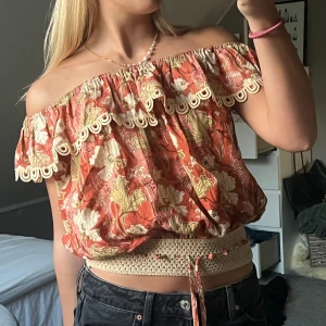 Blommig offshoulder topp från Kitsch & Pop Edition - Säljer en superfin blommig offshoulder topp från Kitsch & Pop Edition i storlek S. Toppen har en härlig orange färg med blommönster och spetsdetaljer vid ärmslut och nederkant. Perfekt för sommarens fester eller en dag på stan. Den har en bekväm passform och är lätt att matcha med jeans eller kjol.💕 hör av er om fler bilder🤗