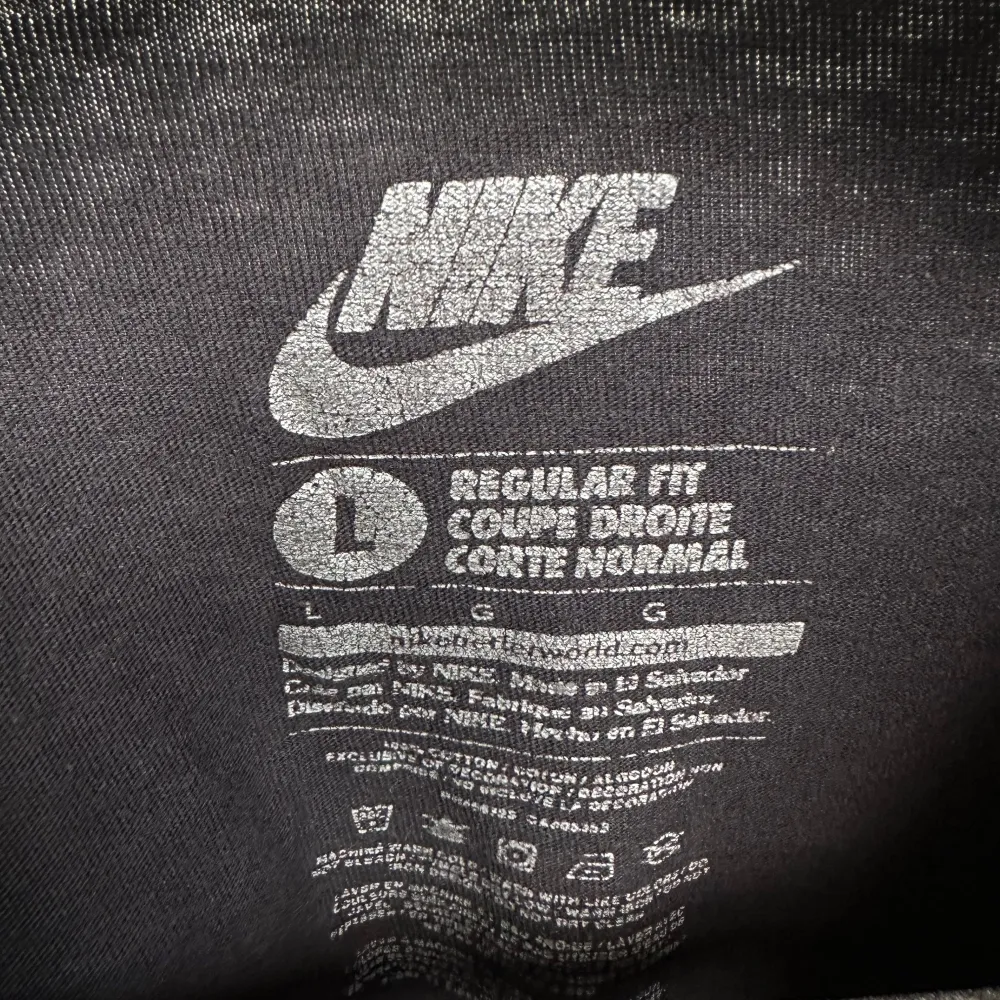 Säljer en svart t-shirt från Nike i storlek L. Den har en broderad vit Nike-logga på bröstet. T-shirten är i bra skick men har några små fläckar. Perfekt för vardagsbruk eller träning.. T-shirts.