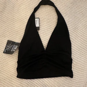 Halterneck topp - Svart halterneck top från nelly, helt ny med prislappar på