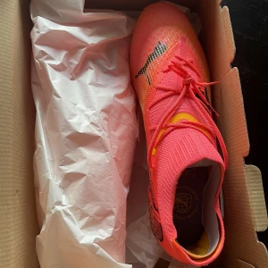 Puma future 43 - Säljer ett par grymma fotbollsskor från Puma i en skarp rosa färg med svarta detaljer. Skorna har snörning och en tight passform för bästa kontroll på planen. De är i nytt skick och kommer i originalkartong. 