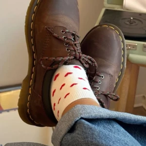 Bruna läderskor från Dr. Martens - Säljer ett par klassiska bruna Dr. Martens i läder. De har den ikoniska gula sömmen och snörning framtill. Skorna är i bra skick med lite slitage som ger dem en cool vintage-look. Perfekta för både vardag och fest! 