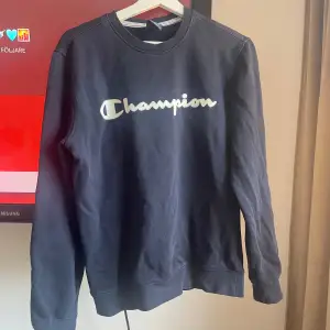 Säljer en svart sweatshirt från Champion i storlek S. Tröjan har en klassisk design med Champion-loggan tryckt på framsidan. Perfekt för en avslappnad stil och passar bra till både jeans och träningsbyxor. Skön och bekväm för vardagsbruk!