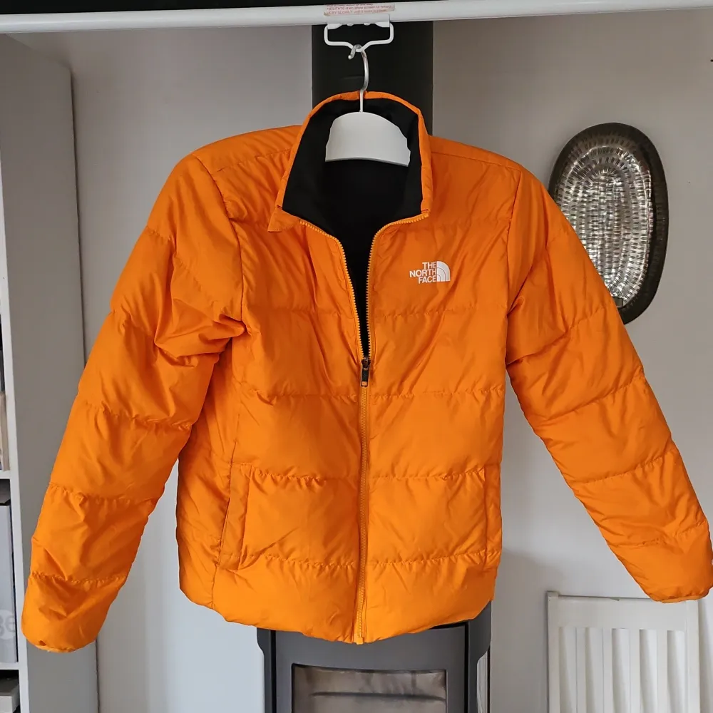 Säljer en supercool vändbar jacka från The North Face. Ena sidan är knallorange och den andra är svart med orange detaljer. Perfekt för höst och vår! Jackan har en dragkedja och är långärmad. Den är i mycket bra skick och redo för nya äventyr!. Jackor.