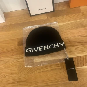 Svart mössa från Givenchy - Ny och oanvänd svart mössa från Givenchy i ull och kaninhår. Perfekt för att hålla dig varm och stilren under kyliga dagar. Den har Givenchy-loggan broderad i vitt framtill. Tillverkad i Italien, vilket garanterar hög kvalitet och lyxig känsla.