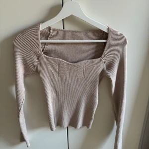 Beige ribbad tröja - Säljer en superfin beige ribbad tröja med lång ärm och en unik fyrkantig halsringning. Perfekt för både vardag och fest! Den är i bra skick och passar perfekt till höst- och våroutfits. Skön och stretchig, så den sitter snyggt på kroppen. Hör av dig vid intresse! 🌟