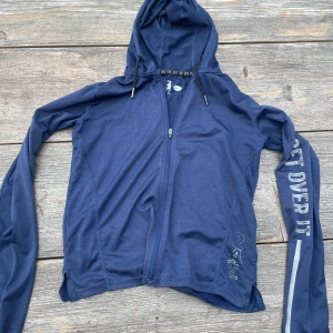 Mörkblå hoodie med dragkedja  - Säljer en mörkblå tränings hoodie i bra skick. Den har en dragkedja framtill för endast 20 kr. Något sliten vid fållen men fortfarande snygg och bekväm. Passar perfekt för vardagsbruk eller lätt träning.